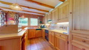 a large kitchen with wooden cabinets and a window at Warm chalet with a nice exterior in Les Marécottes in Les Marécottes