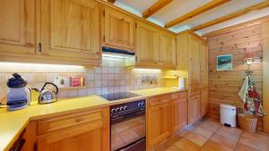 a kitchen with wooden cabinets and a stove at Warm chalet with a nice exterior in Les Marécottes in Les Marécottes