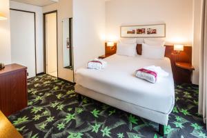 a hotel room with a large white bed with two pillows at Mercure Lourdes Impérial in Lourdes