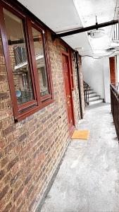 an empty hallway of a brick building with a red door at Your home from home in London