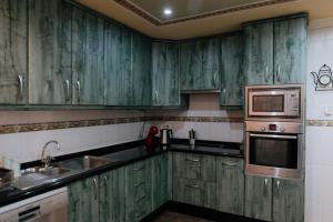 uma cozinha verde com armários verdes e um micro-ondas em Endless Summer Vibes em Adeje