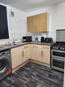 a kitchen with wooden cabinets and a washer and dryer at Your home from home in London