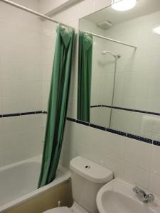 a bathroom with a green shower curtain and a toilet at City View Hotel in London