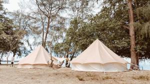2 tentes sur une plage avec des arbres en arrière-plan dans l'établissement Rustika Glamping, à Kampong Tanjong Che Lahom