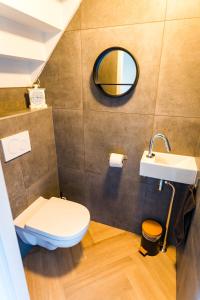 een badkamer met een toilet, een wastafel en een spiegel bij Luxe Veluws Vakantiehuis met JACUZZI in Lunteren