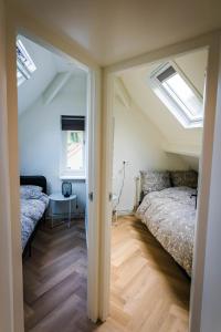 a bedroom with two beds and two windows at Luxe Veluws Vakantiehuis met JACUZZI in Lunteren