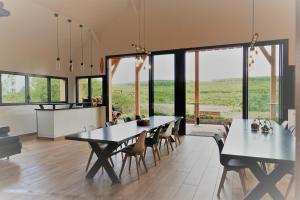 a dining room with two tables and chairs and windows at Gîte de l’Ambiance in Francheville