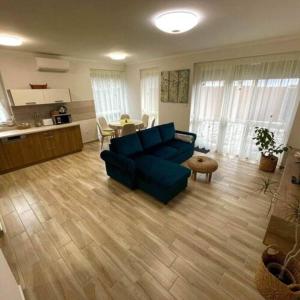 LILIBORI apartman في بابا: غرفة معيشة مع أريكة زرقاء ومطبخ