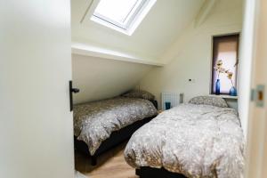 2 Betten in einem Schlafzimmer im Dachgeschoss mit Fenster in der Unterkunft Luxe Veluws Vakantiehuis met JACUZZI in Lunteren