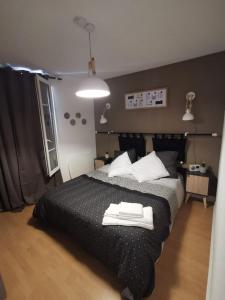 una camera da letto con letto nero e cuscini bianchi di LE COSY - Appartement Pontoise Cosy Calme a Pontoise