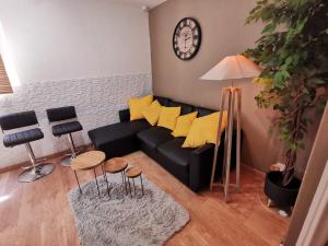 un soggiorno con divano nero e cuscini gialli di LE COSY - Appartement Pontoise Cosy Calme a Pontoise
