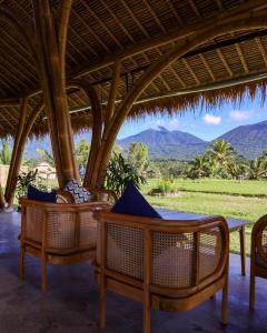 eine Terrasse mit einem Tisch, Stühlen und Bergen in der Unterkunft Nadi Nature Resort - Adults Only in Tabanan