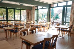 un restaurante con mesas y sillas de madera y ventanas en Hotel Adler en Lauda-Königshofen
