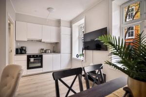 a kitchen with white cabinets and a table and chairs at Meltzers Apartments in Bergen