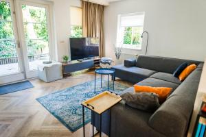 uma sala de estar com um sofá e uma televisão em Luxe vakantiehuis in het bos met jacuzzi en sauna em Lunteren