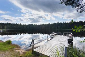 a wooden dock on a lake with clouds in the water at Lomaperkkiö Cottages in Kajaani
