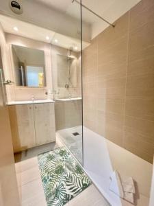 uma casa de banho com uma cabina de duche em vidro e um lavatório. em Les Rivages 2P terrasse parking em Menton