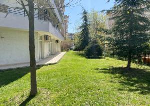 a green yard with trees and a building at Kims One-bed Apart for rent at Sunny Beach Resort in Sunny Beach