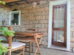 a wooden table and chairs next to a brick wall at La Casetta in Padru