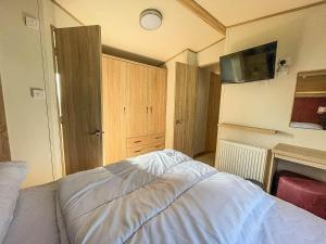 1 dormitorio con 1 cama y TV en la pared en 6 Berth Caravan At California Cliffs With Decking In Scratby Ref 50015kc, en Great Yarmouth