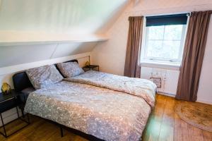 um quarto com uma cama e uma janela em Luxe vakantiehuis in het bos met jacuzzi en sauna em Lunteren