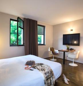 a hotel room with a bed and a desk and a tv at L'Ermitage Hôtel Cuisine-À-Manger in Saint-Cyr-au-Mont-dʼOr