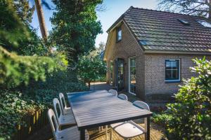 een houten tafel en stoelen voor een huis bij Luxe vakantiehuis in het bos met jacuzzi en sauna in Lunteren