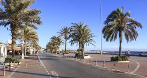 uma rua com palmeiras e o oceano no fundo em Dar Khalifa Airport em Nouaseur