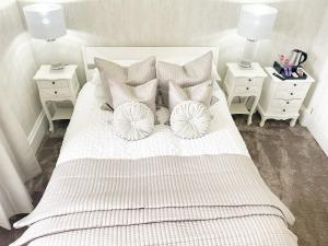 1 dormitorio con 1 cama blanca con almohadas y 2 mesitas de noche en Kenavara House, en Oban