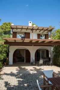 una casa con un patio con tavoli e sedie di Grand Bleu Porto Heli Beachfront House a Porto Heli