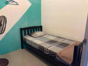 Cama pequeña en habitación con pared verde y blanca en Travellers Diary Guesthouse, en Melaka