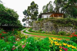 a garden with colorful flowers and a stone wall at De Huts Kodaikanal in Kodaikānāl