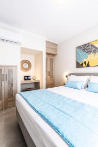 um quarto com uma grande cama branca com lençóis azuis em Bianco Mare Studios-Apartments em Kalivia Poligirou