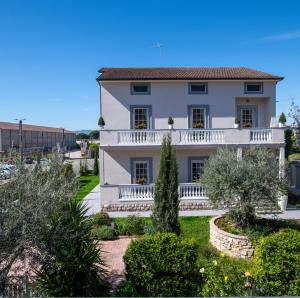 a white house with a balcony and trees at Villa Luce Assisi Rooms & Suites in Assisi