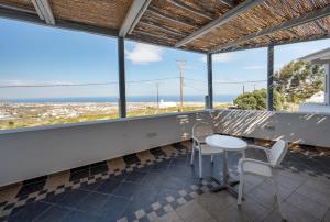 una mesa y sillas en un balcón con vistas al océano en Orizontes Hotel Santorini, en Pirgos
