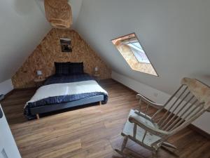 sypialnia z łóżkiem i krzesłem na poddaszu w obiekcie Gîte les 4 sabots de la Baie w mieście Bourseville