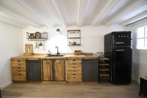 a kitchen with a black refrigerator and wooden cabinets at New design apartment in Barcelona center. in Barcelona