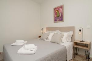 a bedroom with a large white bed with towels on it at Diov Bohali House in Zakynthos Town