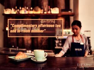 une femme derrière un comptoir avec une tasse de café et une pâtisserie dans l'établissement The Myst Dong Khoi, à Hô-Chi-Minh-Ville