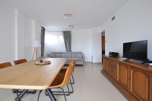 a living room with a wooden table and a television at Santa Clotilde in Lloret de Mar