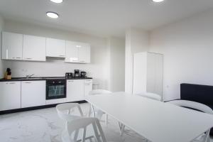 uma cozinha branca com uma mesa e cadeiras brancas em Noa East Residence em Novalja