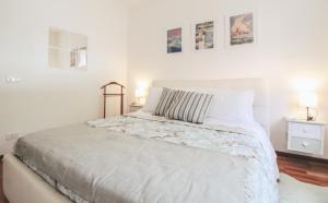 a white bedroom with a bed and two pictures on the wall at Appartamento Angelina in Menaggio
