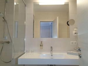 ein Badezimmer mit einem Waschbecken und einem großen Spiegel in der Unterkunft R&R Hotel Strandallee in Baabe