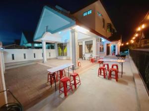 a patio with tables and red stools in front of a house at C01 HomeStay in Rinting Village in Masai