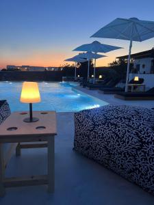 a lamp on a table next to a bed next to a pool at Irene's Residence in Mikonos