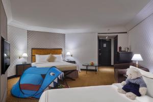 a hotel room with a teddy bear sitting on two beds at Grand Millennium Kuala Lumpur in Kuala Lumpur