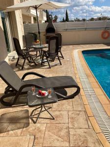 a patio with chairs and a pool with a table and a bowl of fruit at Anna Villa in Protaras