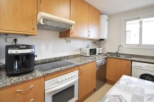 a kitchen with wooden cabinets and a counter top at Santa Clotilde in Lloret de Mar