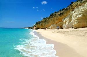 a sandy beach with the ocean and a cliff at Modern studio with swimming pool in Lowlands - 68 m² in Lowlands