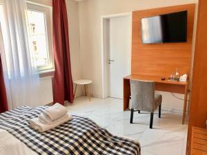a bedroom with a bed and a desk and a television at Hotel Emiliana am Bahnhof in Frankfurt/Main